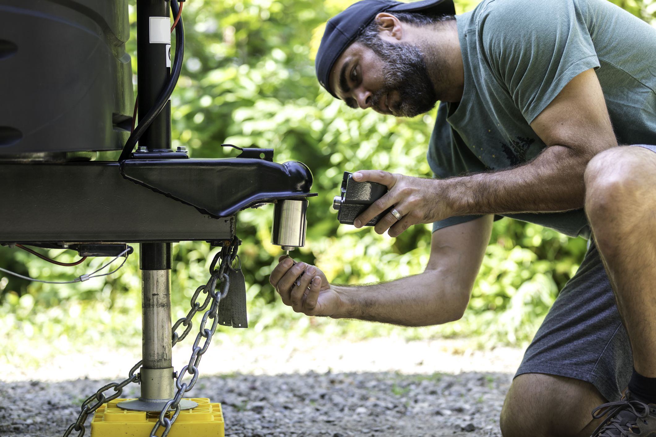 A man is Installing the camper trailer padlock during camping in summer.