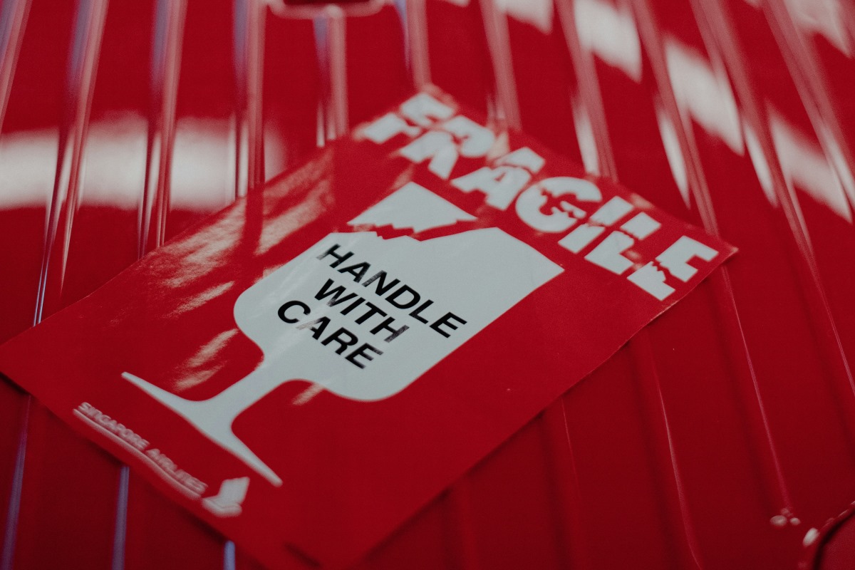 A fragile sticker on a red suitcase.